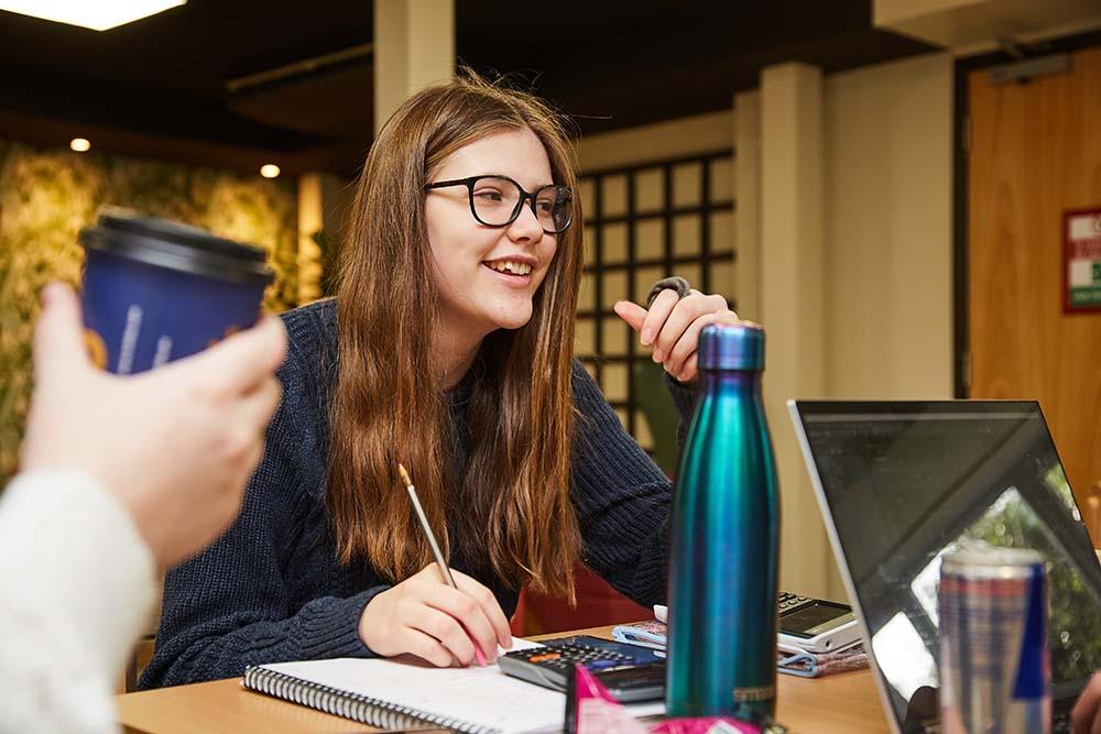 Student socialising with friends while engaging in work